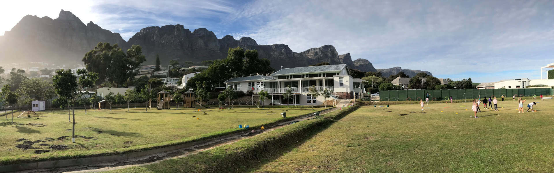 Panoramic view of the Camps Bay Primary campus and sports field beneath the mountains