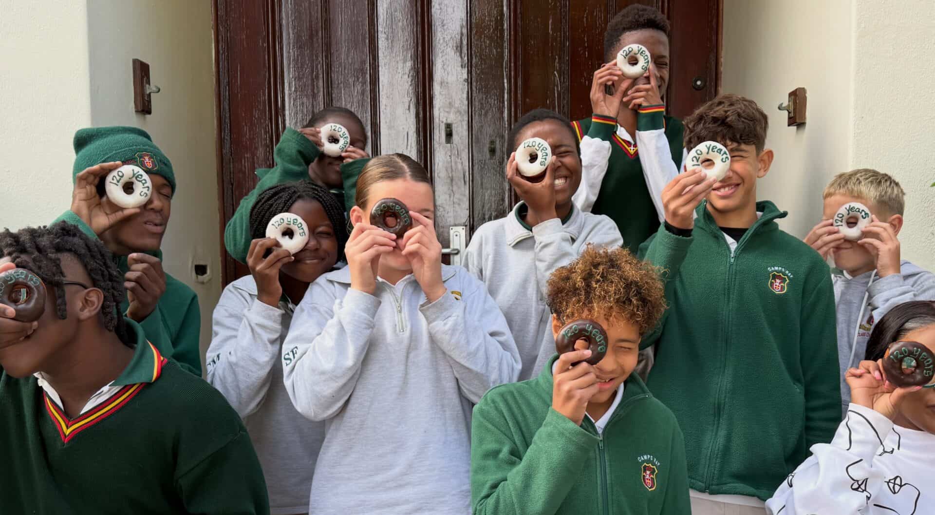 Learners holding up doughnuts to celebrate 120 years of Camps Bay Primary