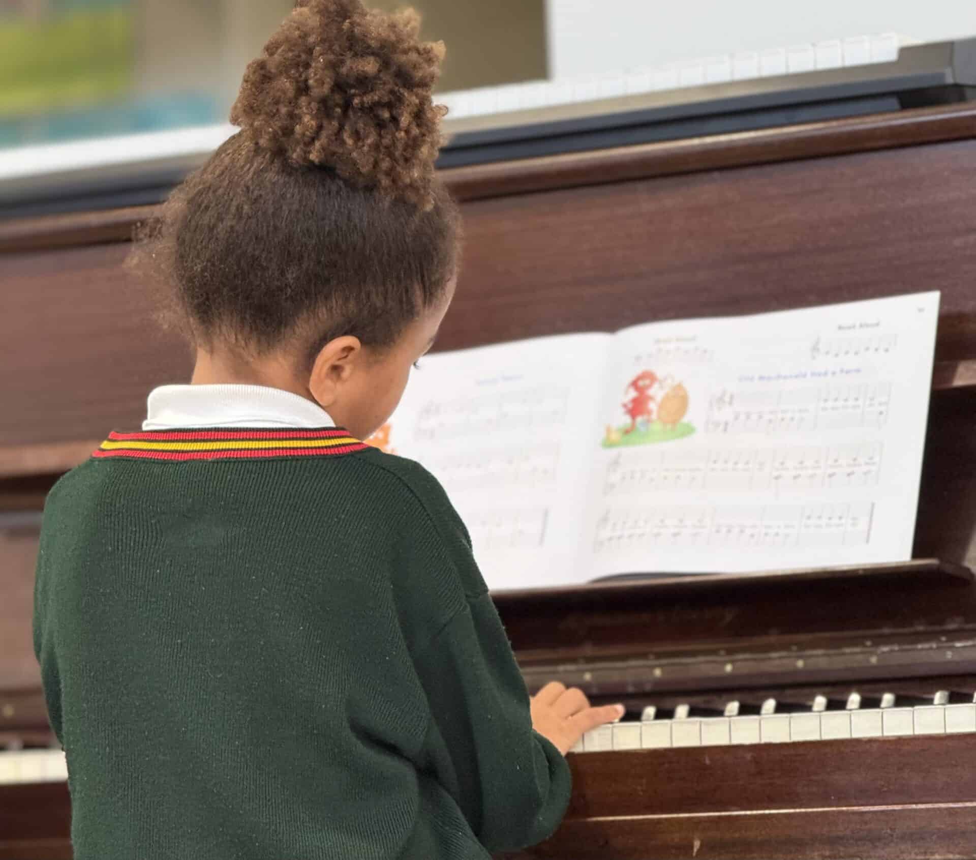 A Camps Bay Primary learner playing the piano from sheet music