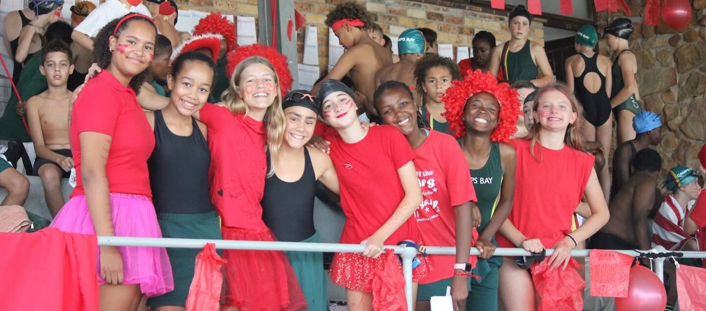 Learners in red house colours cheering from the stands at a school gala