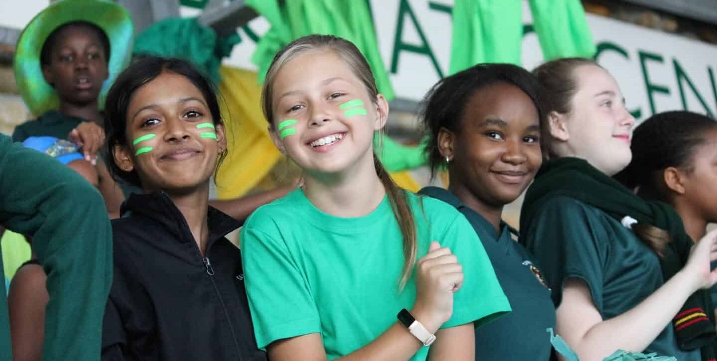 Learners with face paint cheering in green house colours at a school gala