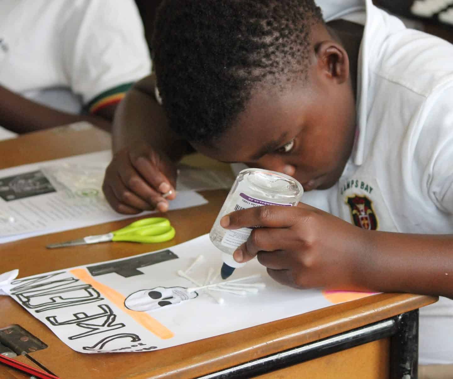 A learner gluing pieces onto an art project in class