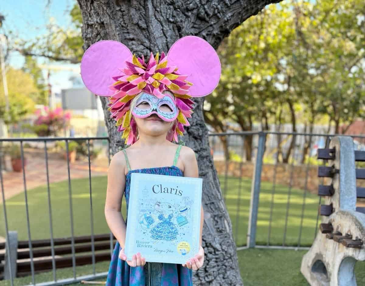 A young learner in a mouse costume holding a book on a book character dress-up day