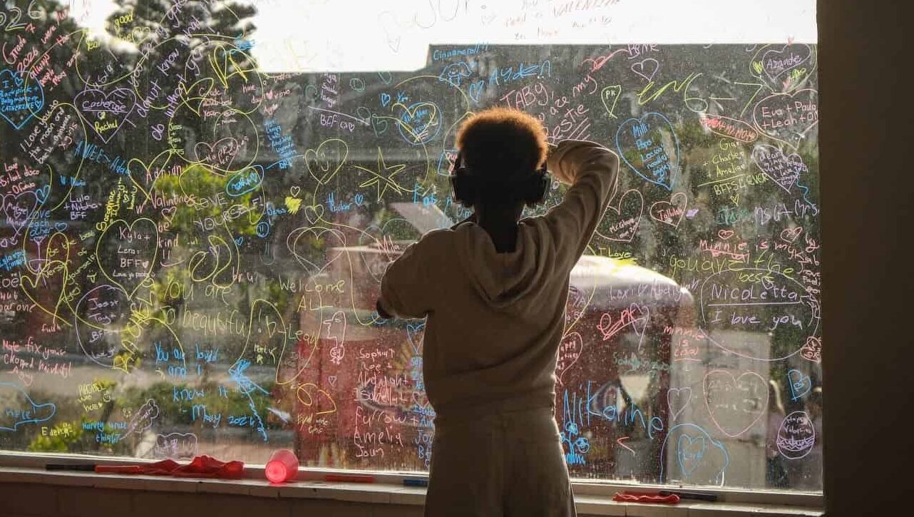 A learner adding to a colourful drawing on a classroom window